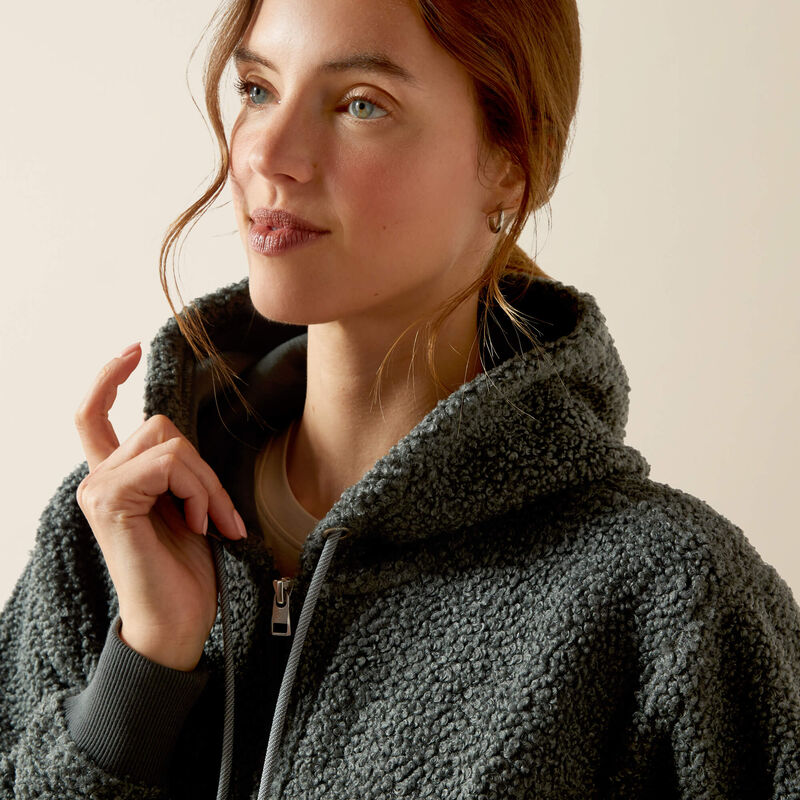 Woman wearing a dark green fleece jacket with a neutral background