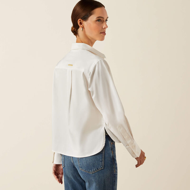 Woman wearing a white shirt and blue jeans against a beige background