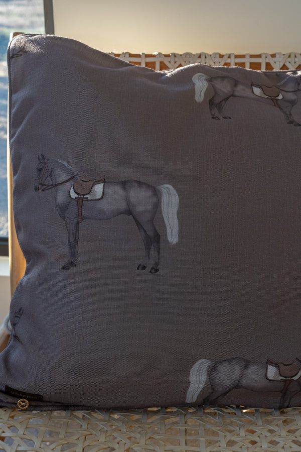 Gray pillow with horse illustrations on a textured surface