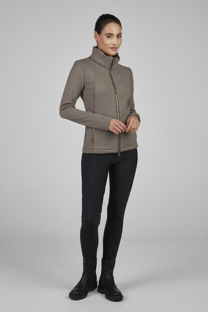 Woman wearing a brown jacket and black pants on a gray background