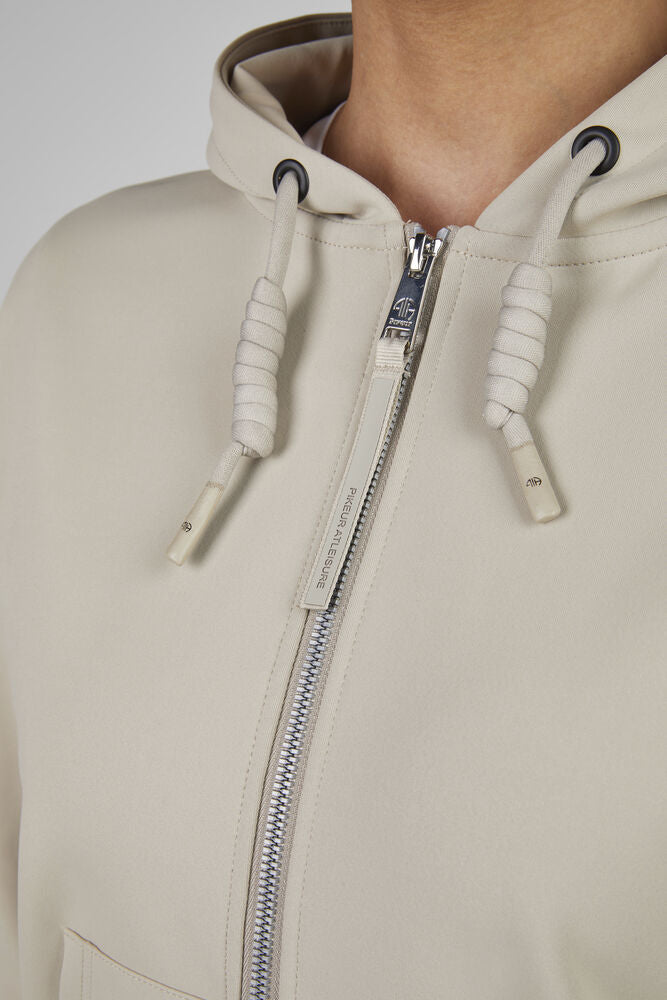 Close-up of a beige hoodie with a zipper and drawstrings on a plain background