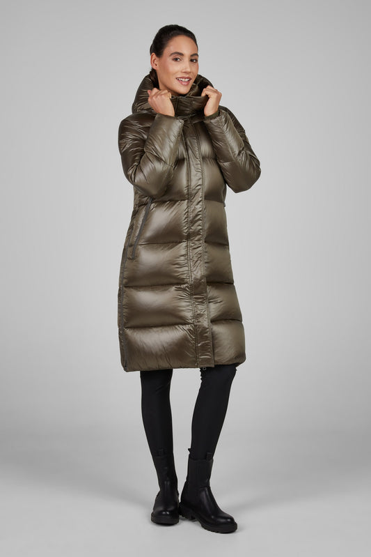 Woman wearing a long metallic brown puffer coat on a gray background