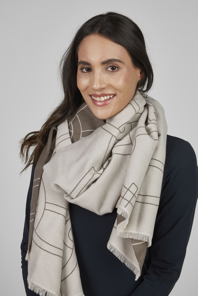 Woman wearing a beige and brown patterned scarf on a plain background