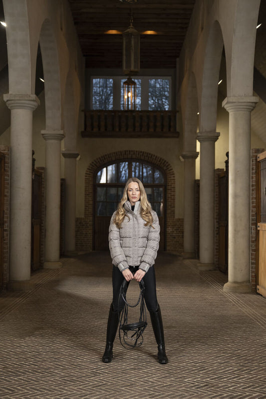 Woman holding skates in a large, open hall with high ceilings and arches.