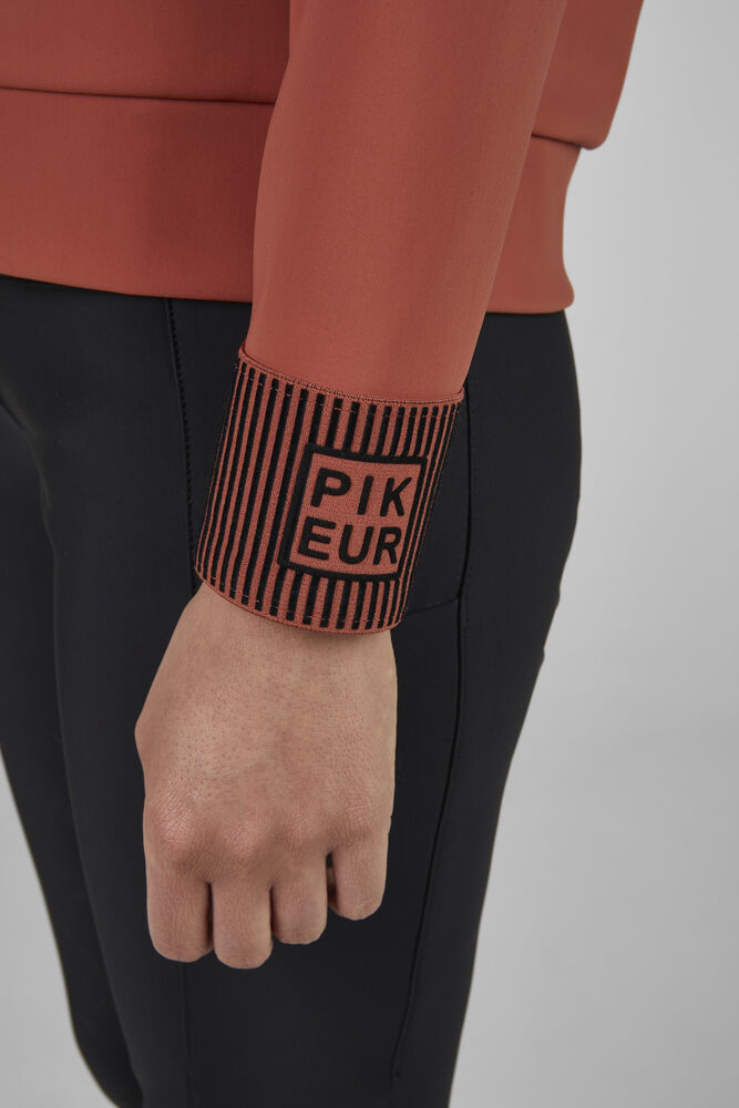 Person wearing a hoodie with 'PIKEUR' branding on the sleeve on a plain background