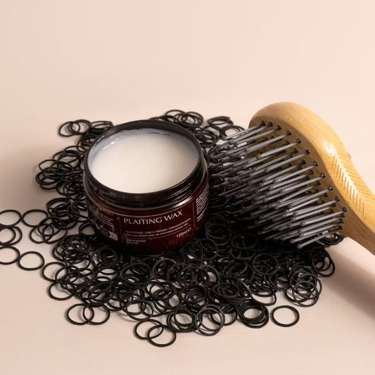 Plaiting wax jar with a wooden comb and hair ties on a beige background