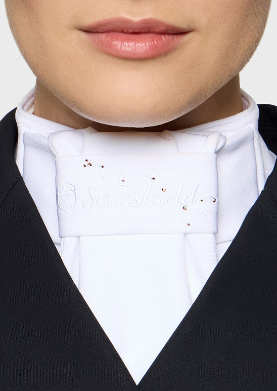 A close-up of a person wearing a white formal neckwear piece with small rhinestone embellishments, styled with a white shirt and black jacket.