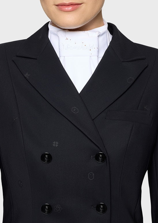 Close-up of a person wearing a structured double-breasted blazer in very dark navy or black, paired with a white high-neck collar blouse. The blazer has notched lapels, dark buttons, and subtle tonal embroidered geometric motifs.
