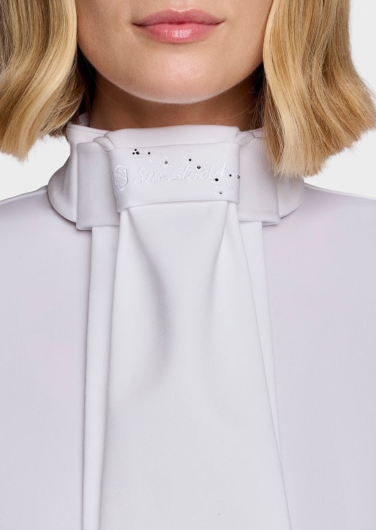 Close-up of a model wearing a white high-neck blouse with a large bow detail and small rhinestone embellishments on the collar.