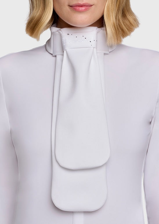 A close-up of a model wearing a high-neck, structured white blouse with a large central bow or pleated front detail and small rhinestone embellishments at the collar.