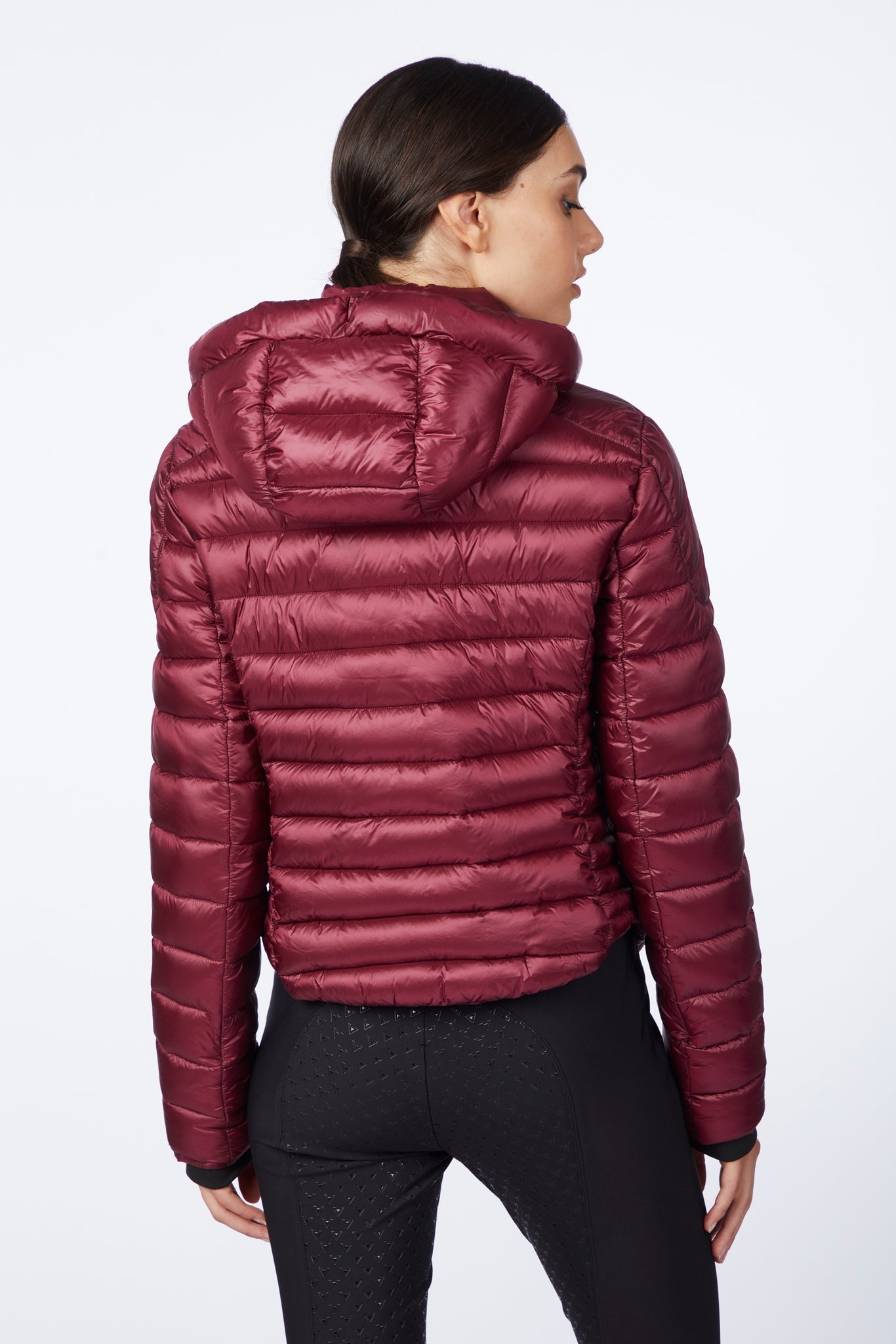 Person wearing a maroon puffer jacket on a white background