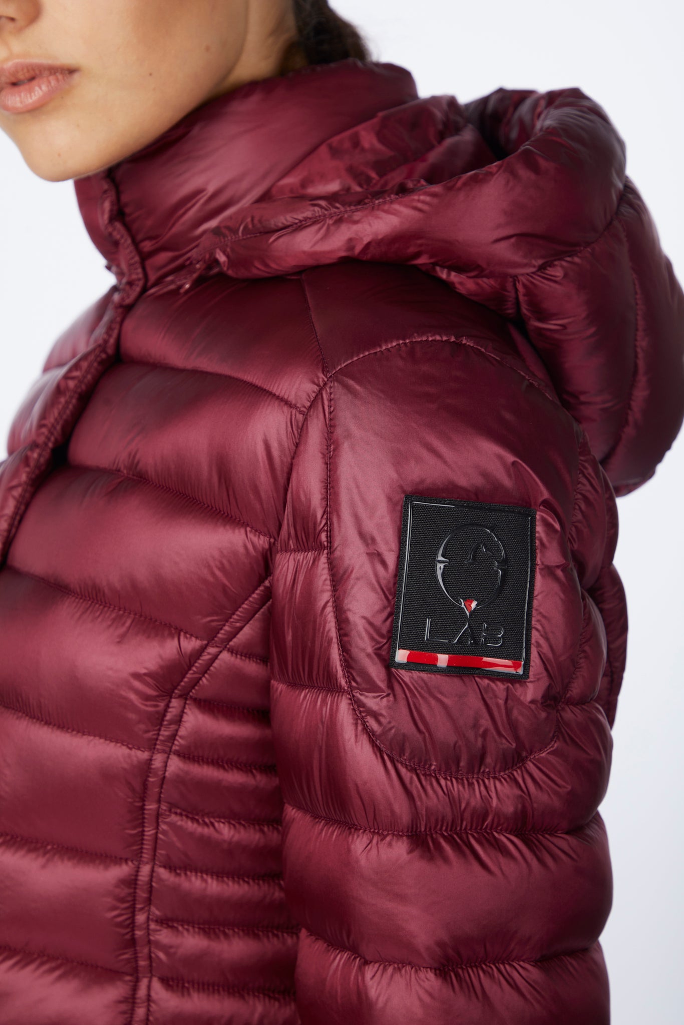Maroon puffer jacket with a brand logo on a white background