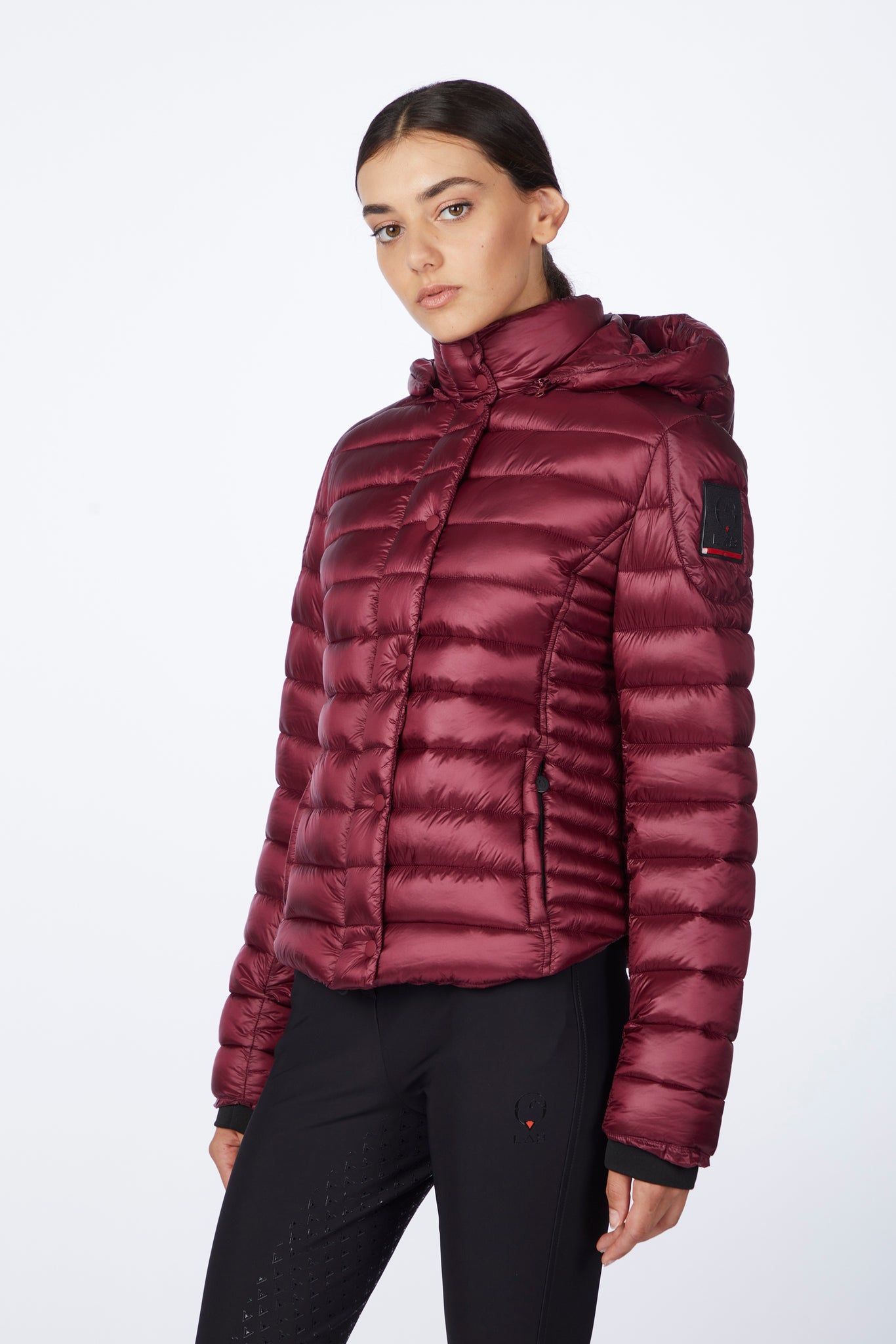 Person wearing a maroon puffer jacket on a white background