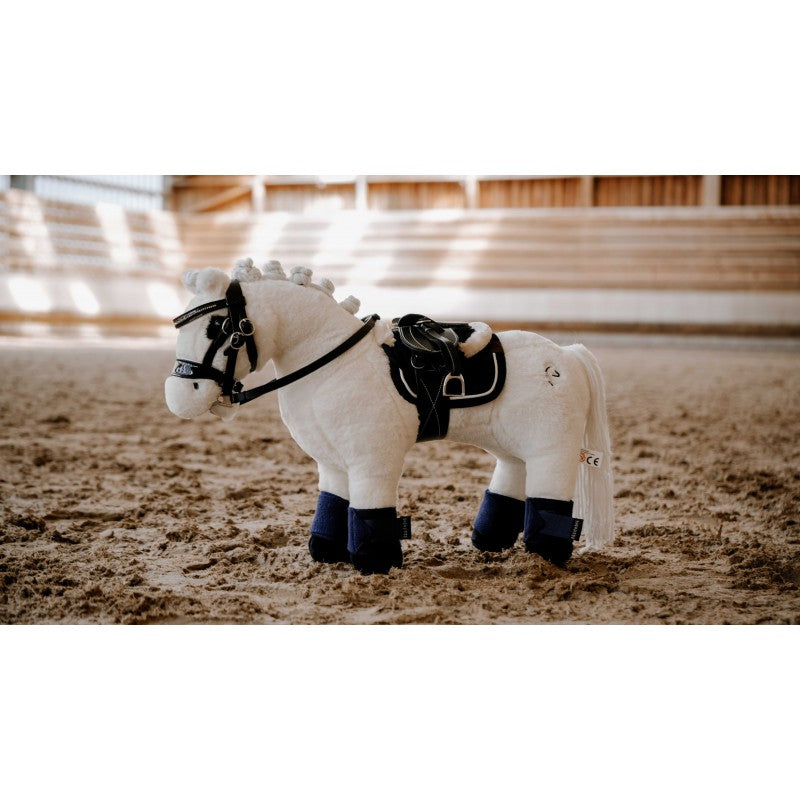 White toy horse with black details in an indoor riding arena