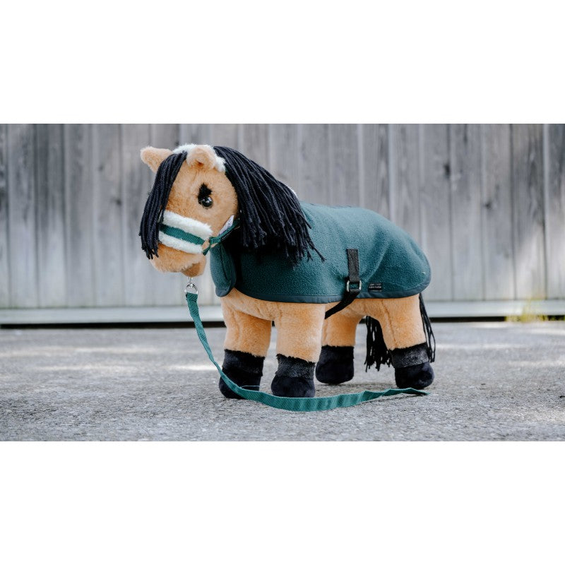 Plush toy horse with a green blanket and reins on a wooden floor.