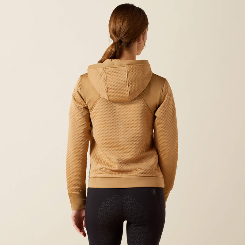Person wearing a beige quilted hoodie on a plain background