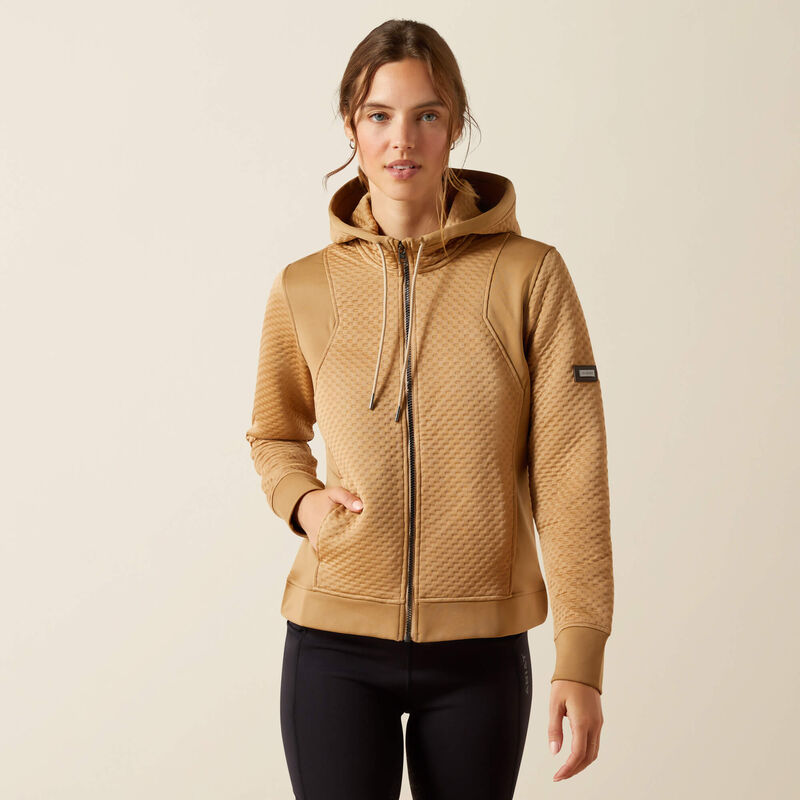 Woman wearing a beige quilted jacket with a brand logo on a beige background