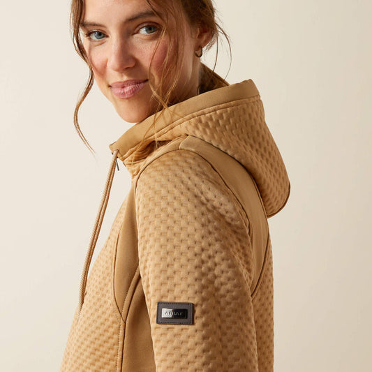 Woman wearing a beige quilted jacket with a brand logo on a beige background