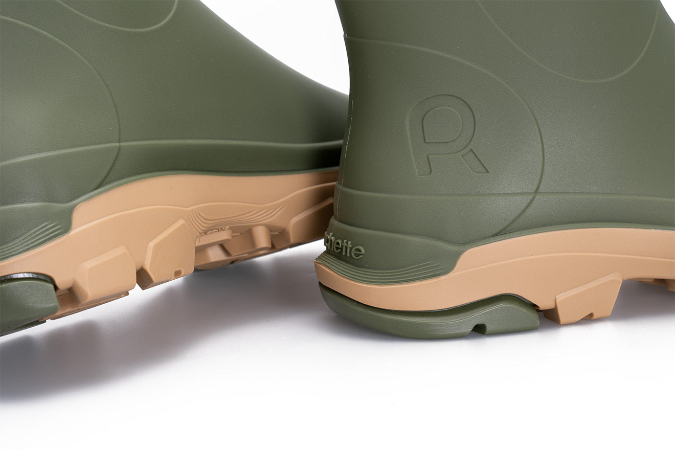 Green rubber boots with tan soles on a white background