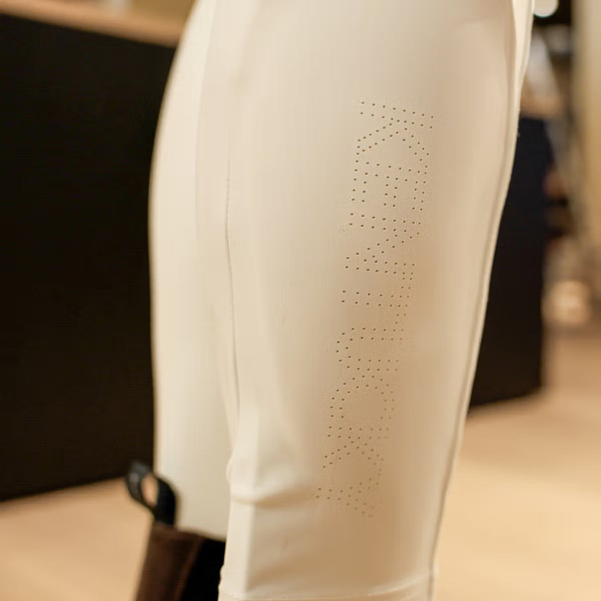 Close-up of a beige garment with small embellishments on a blurred background
