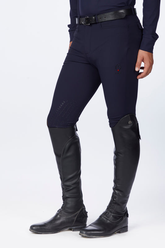 Person wearing navy riding pants and black riding boots on a white background