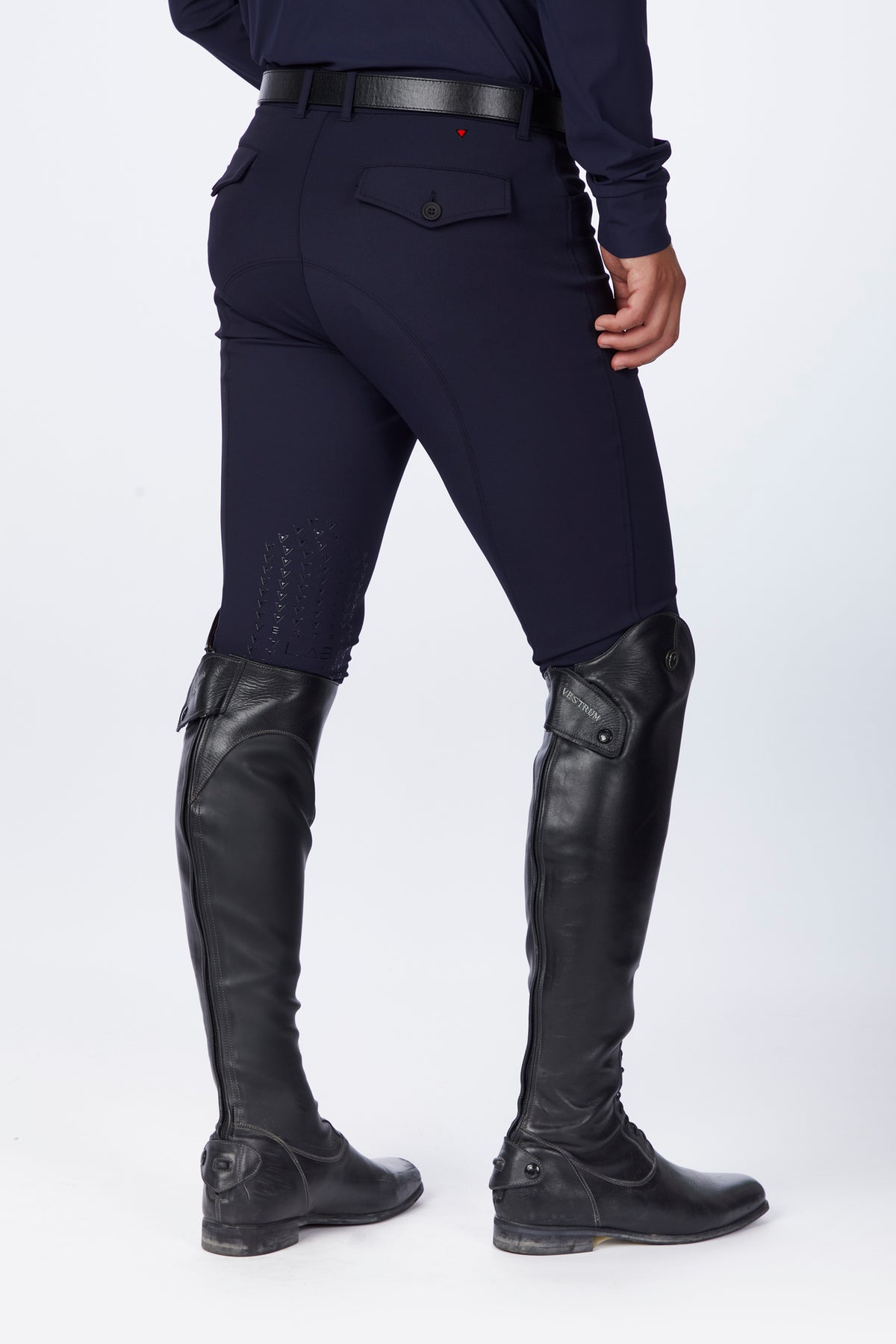 Person wearing navy riding pants and black riding boots on a white background