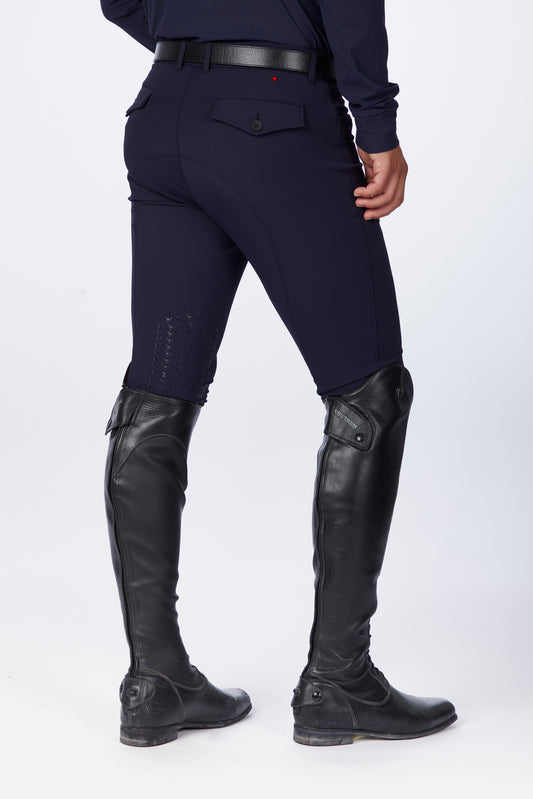 Person wearing navy riding pants and black riding boots on a white background