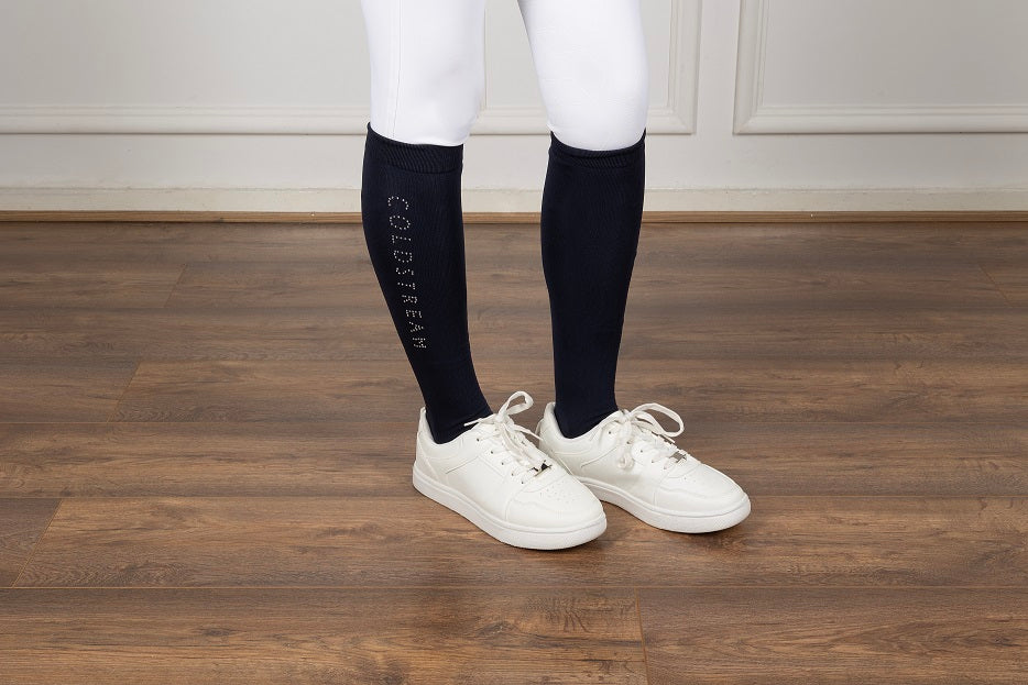 Pair of navy socks and white trainers on a wooden floor