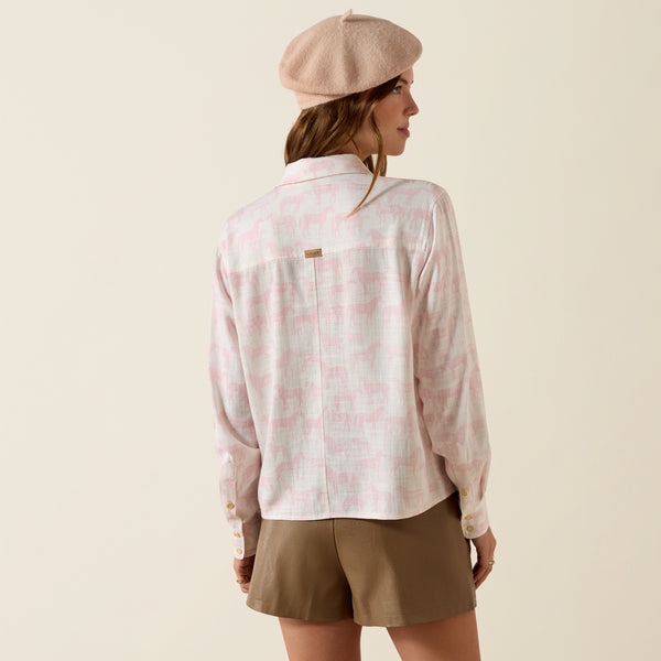 Woman wearing a light pink patterned shirt and beige shorts with a beige beret on a beige background