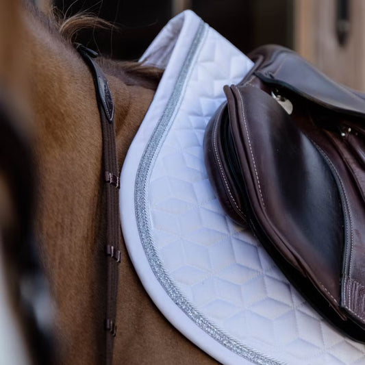 Close-up of a horse saddle with a white quilted pad on a brown horse.