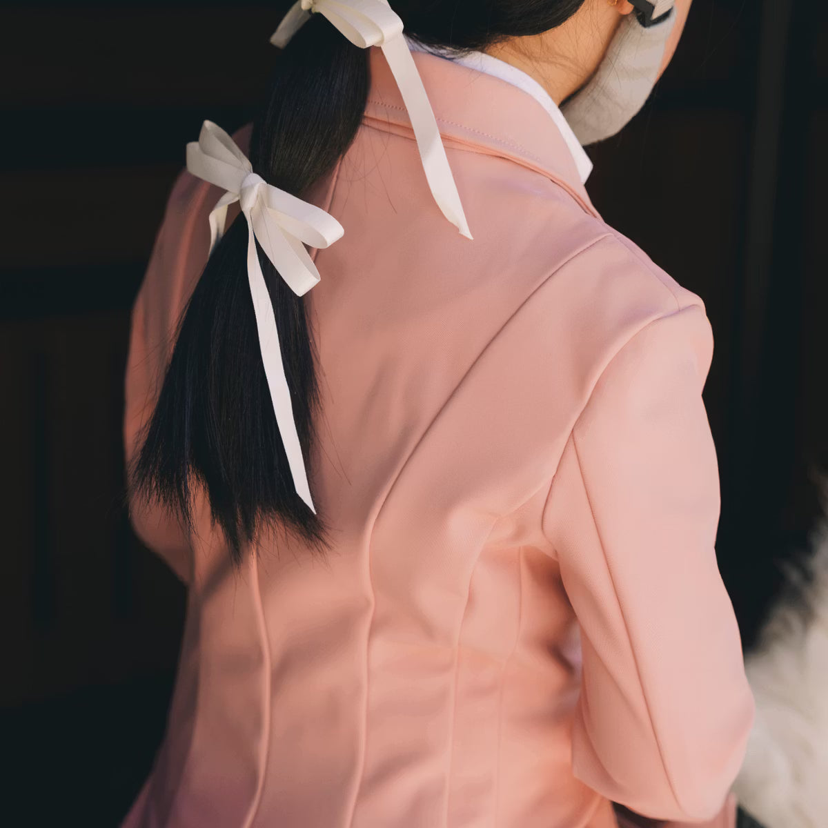Person wearing a pink equestrian shirt with a dark background