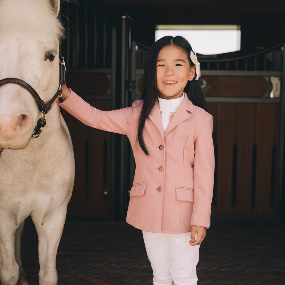 Person wearing a pink equestrian shirt with a dark background
