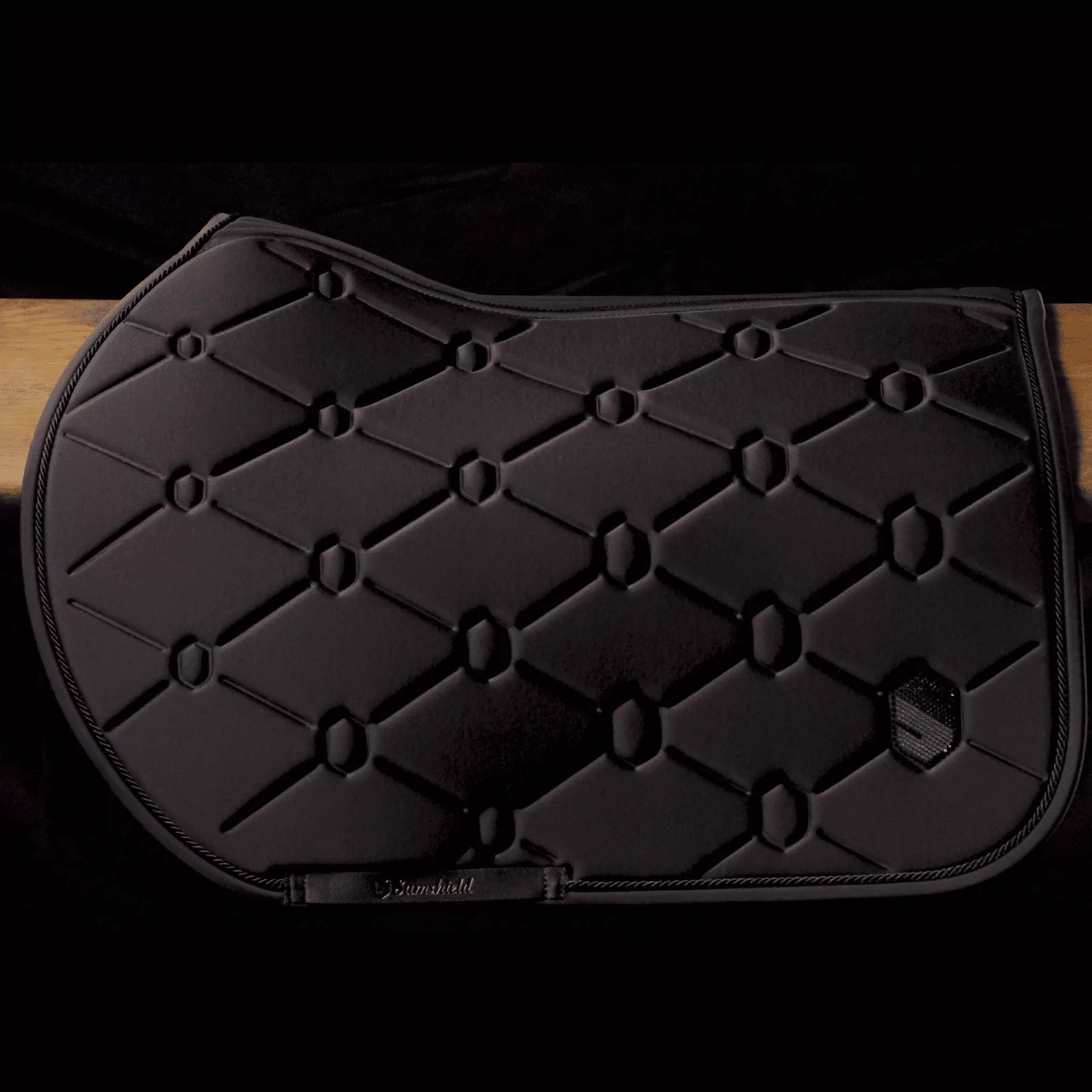 Black saddle pad with diamond pattern on a dark background