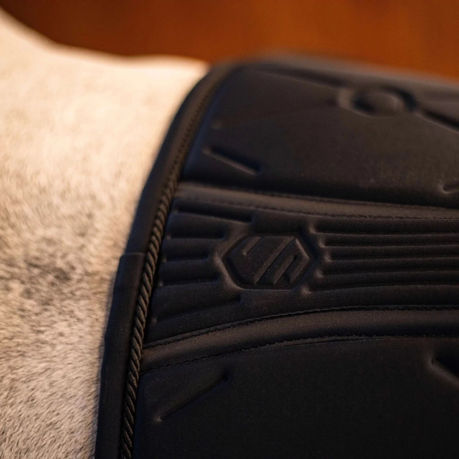 Detail of the spine of a black saddle pad with a blurred background
