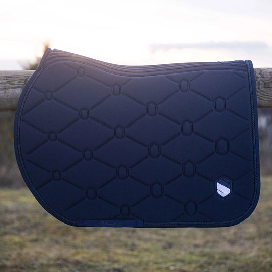 Navy quilted saddle pad on a wooden fence with a blurred natural background