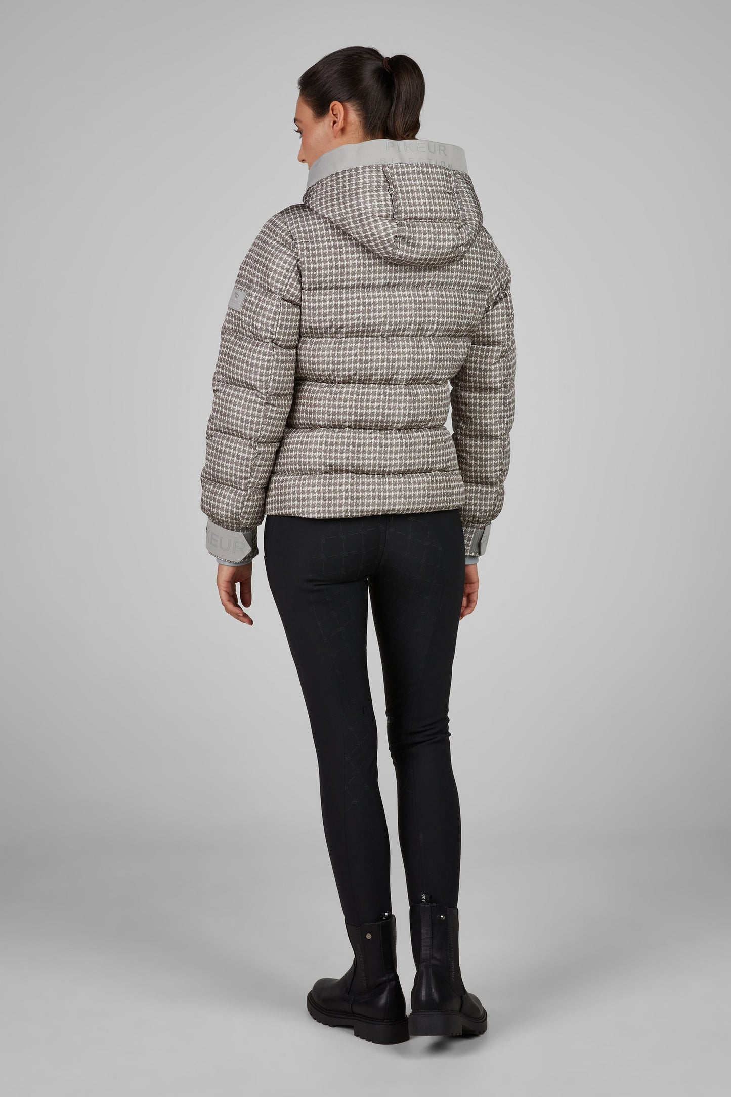 Person wearing a checkered puffer jacket on a gray background