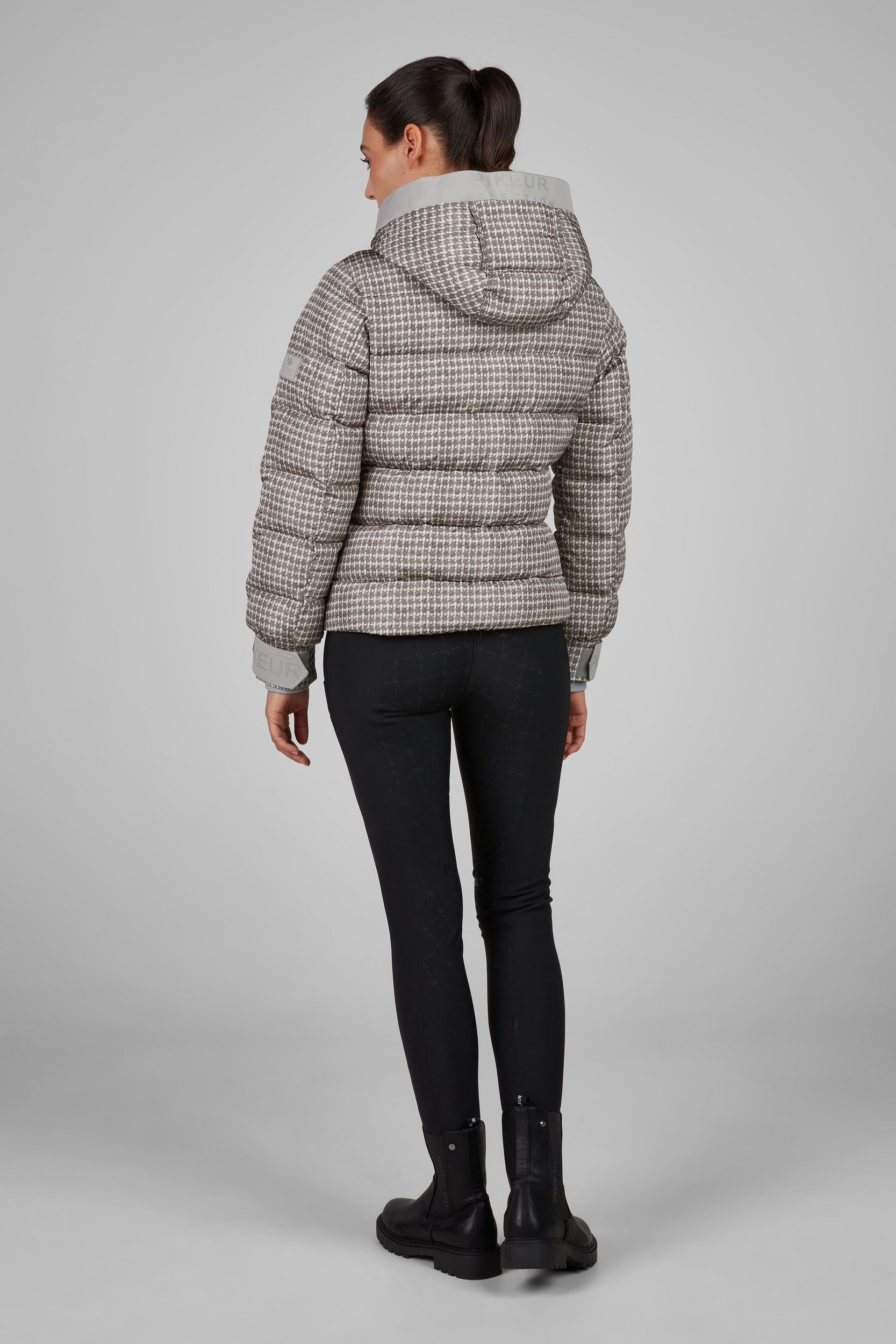 Person wearing a checkered puffer jacket on a gray background