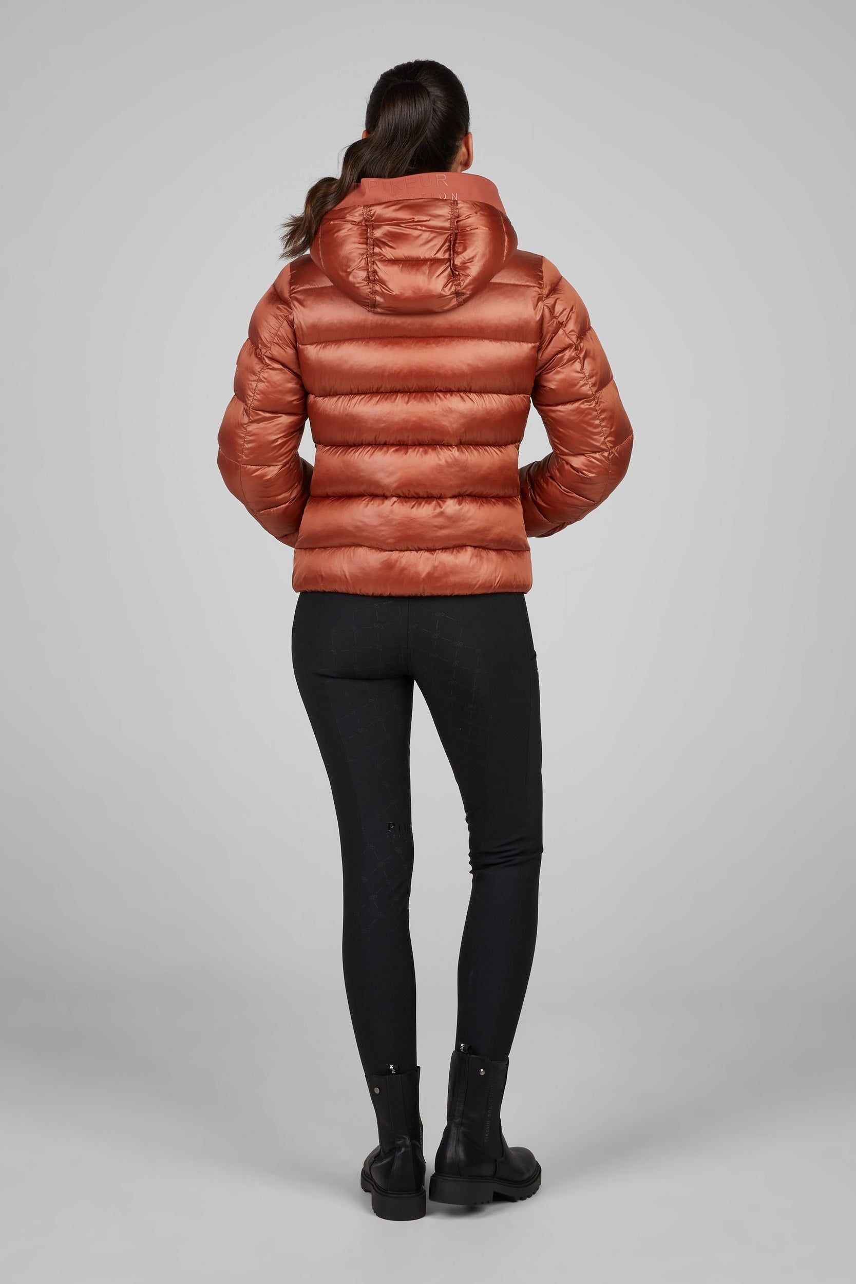 Person wearing a rose puffer jacket on a gray background