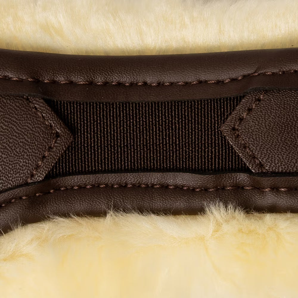 Close-up of brown leather girth with stitching on a beige fur background