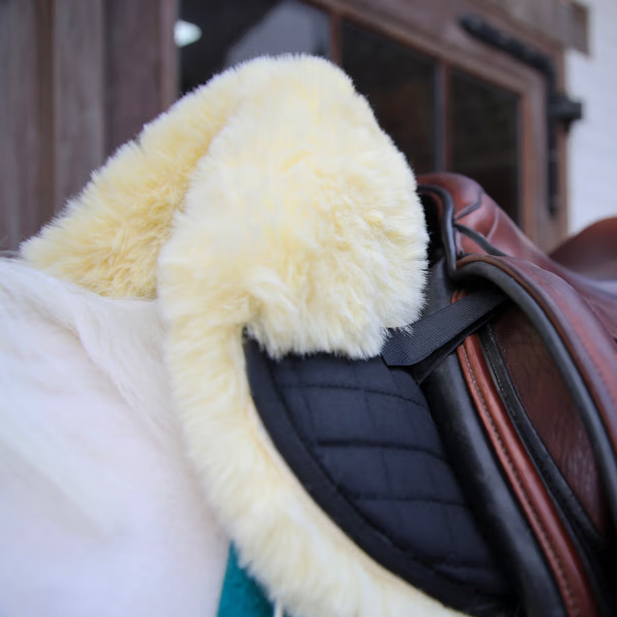 Close-up of a saddle with a yellow sheepskin pad on a blurred background