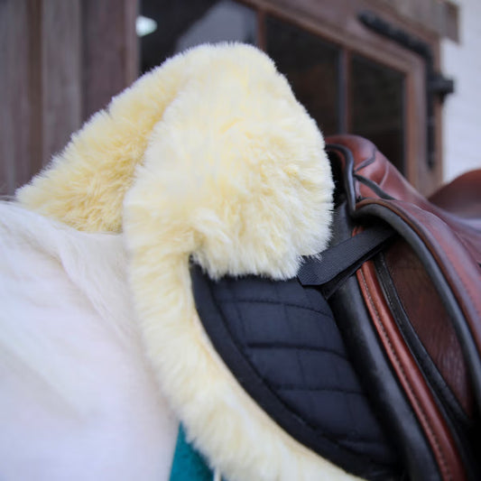 Close-up of a saddle with a yellow sheepskin pad on a blurred background