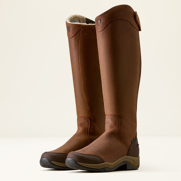 A pair of tall brown leather riding boots with a soft shearling lining visible at the top, shown on a clean off-white background.