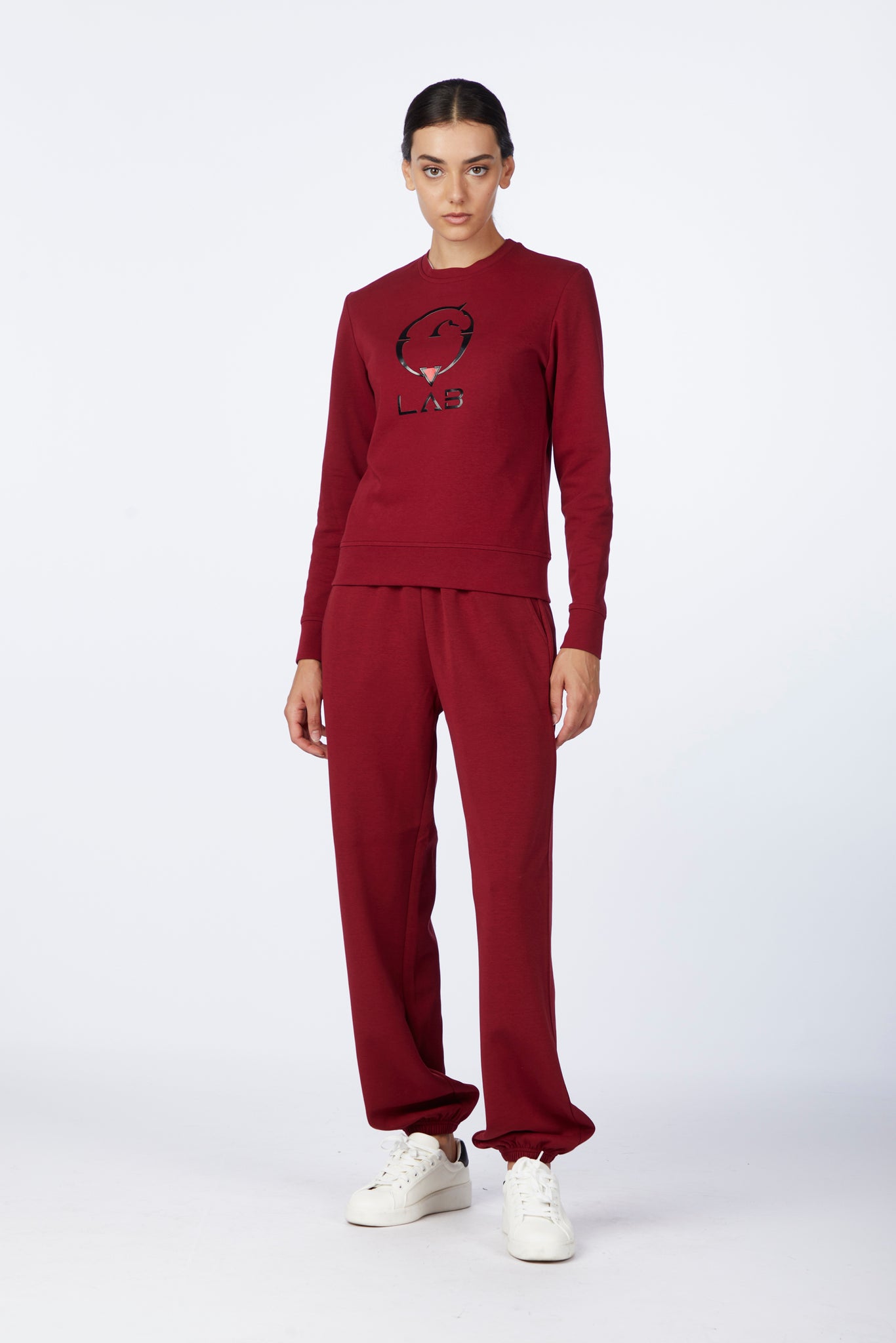 Person wearing a burgundy sweatshirt and pants with a logo on a white background