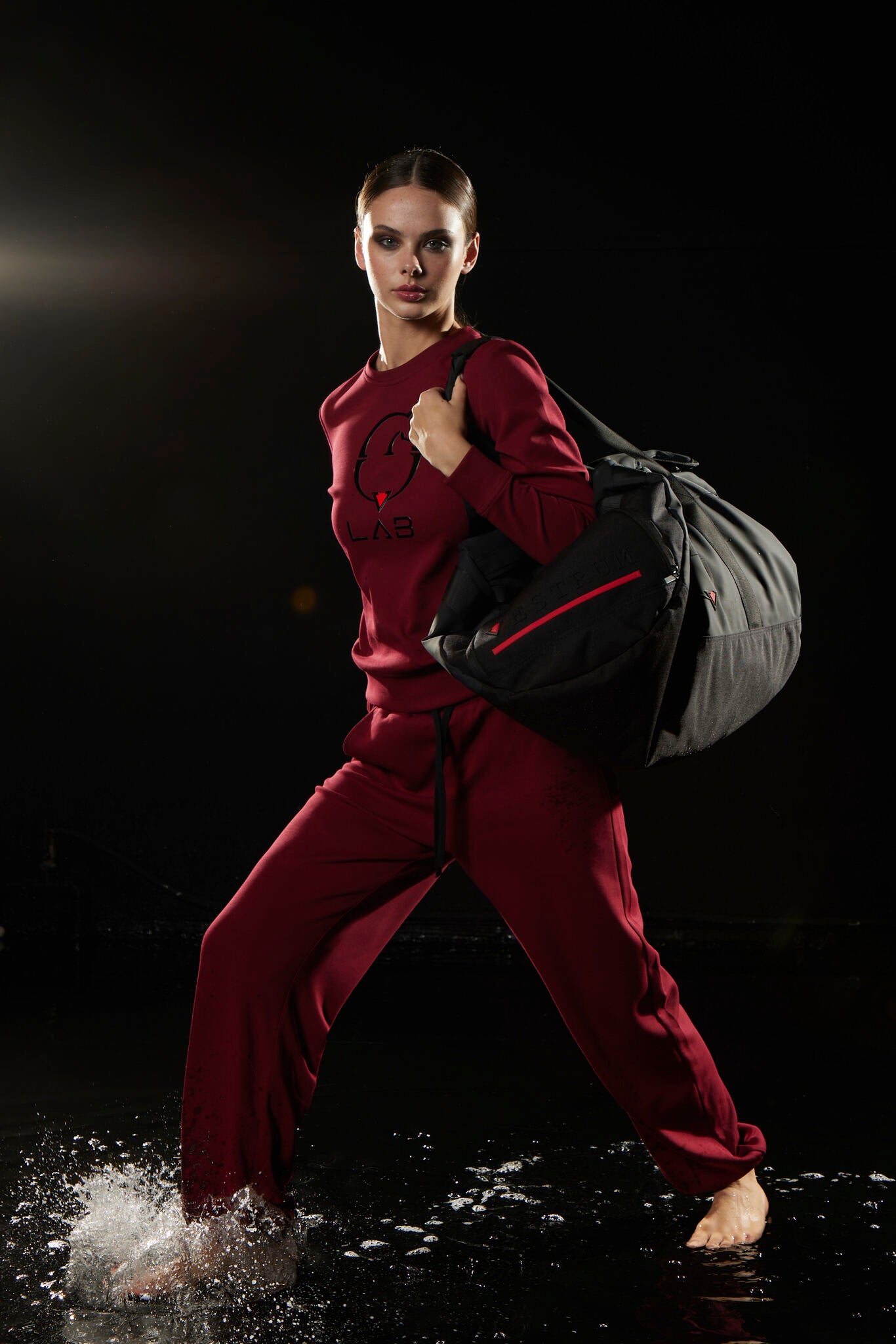 Person in red outfit holding bags in water with dark background