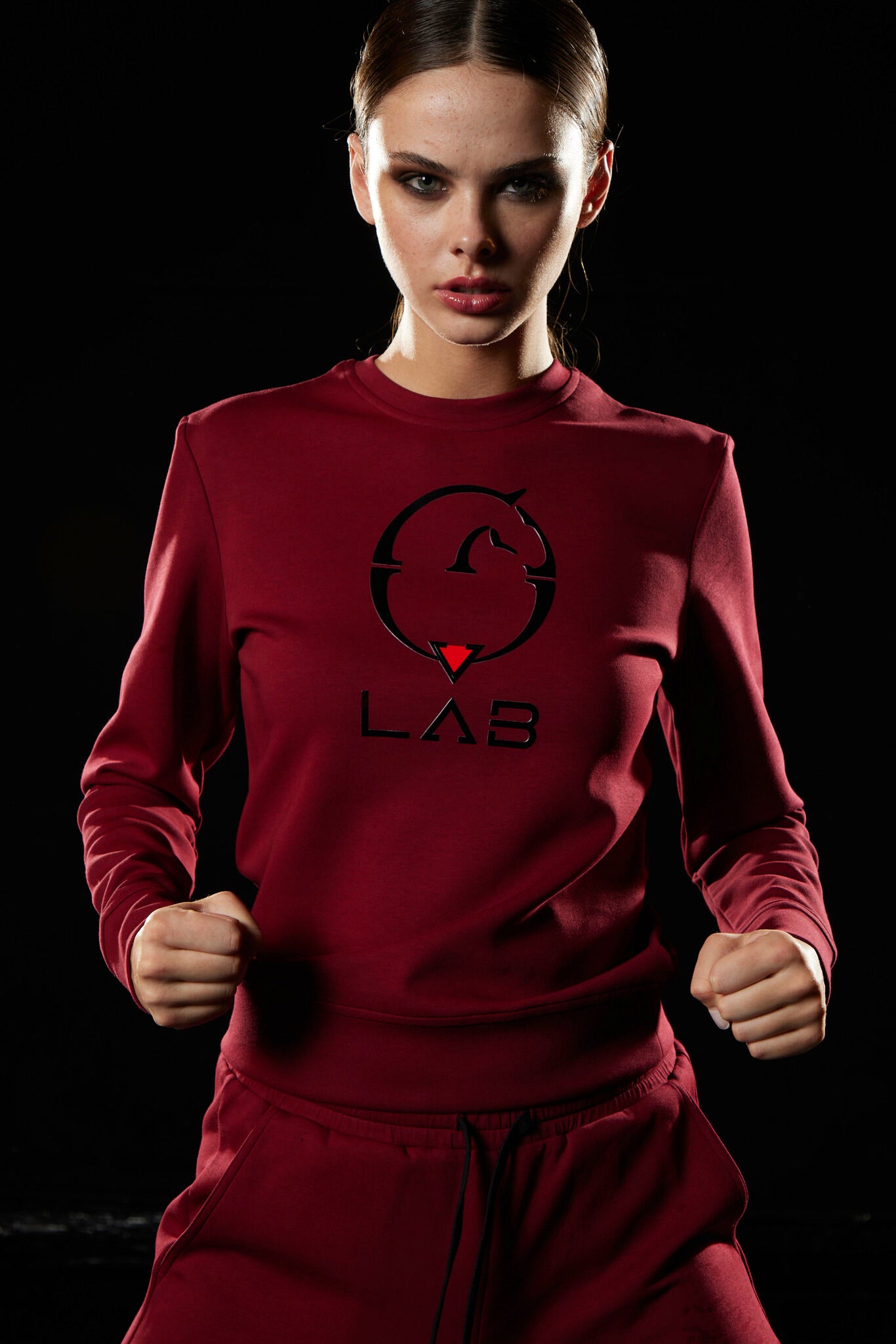 Person wearing a red 'LAB' tracksuit with a black logo on a dark background