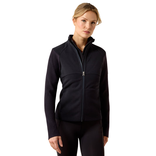 A woman modeling a navy ong-sleeve athletic zip-up jacket with textured knit sleeves and a high collar, set against a plain white background.