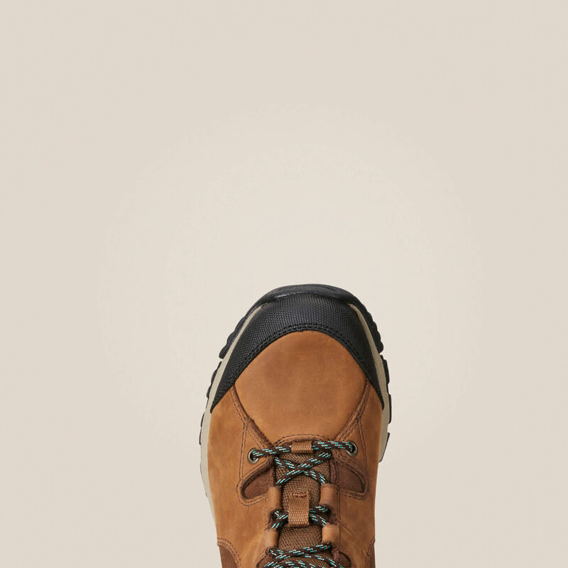 Toe of a brown hiking boot with black sole on a beige background