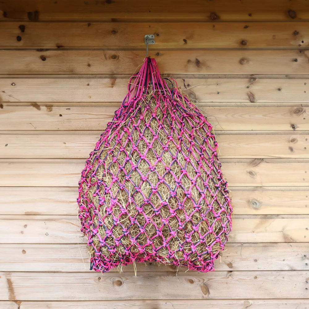 Pink and navy net bag hanging on a wooden wall