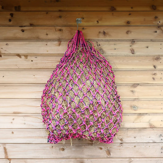 Pink and navy net bag hanging on a wooden wall