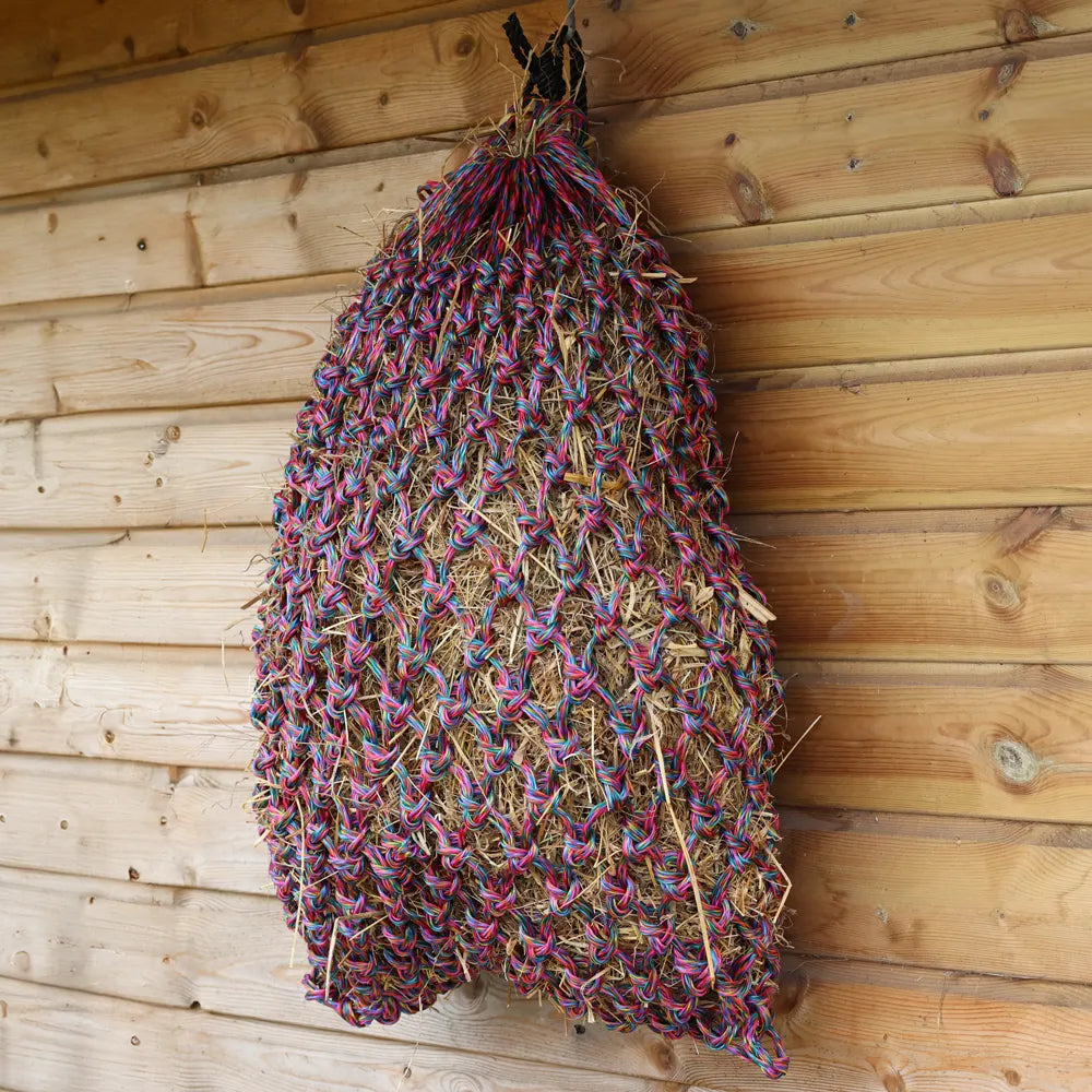Multicolored woven hay net hanging on a wooden wall